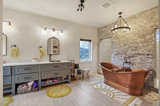 bathroom with a chandelier, vanity, and a tub