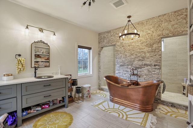 bathroom featuring plus walk in shower, vanity, and a notable chandelier