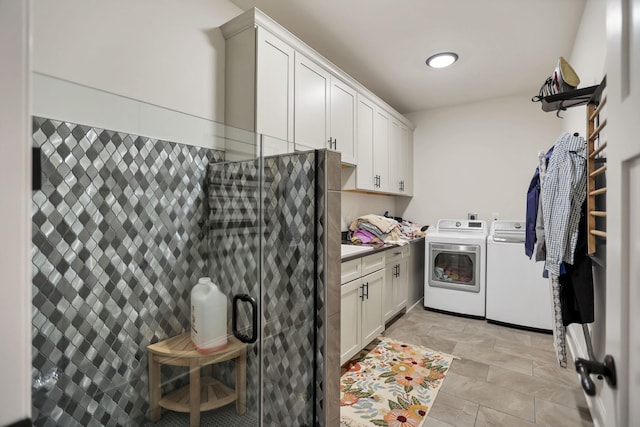 clothes washing area with cabinets and washing machine and clothes dryer