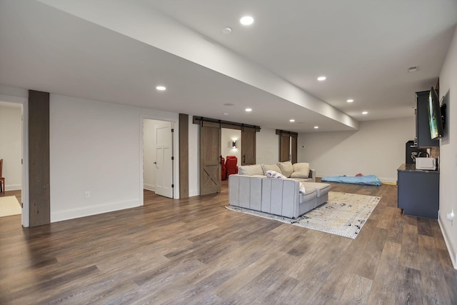 unfurnished living room featuring a barn door and dark wood-type flooring