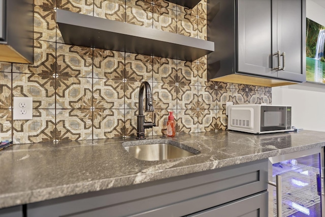 kitchen featuring gray cabinetry, sink, wine cooler, backsplash, and dark stone countertops