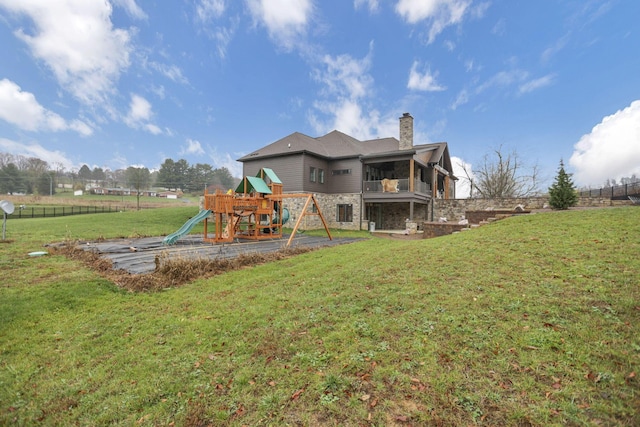 back of property with a lawn, a playground, and a balcony