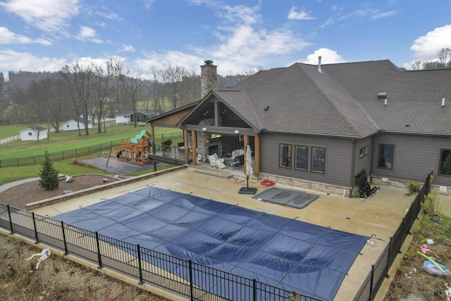 back of property with a lawn, a patio, and a covered pool