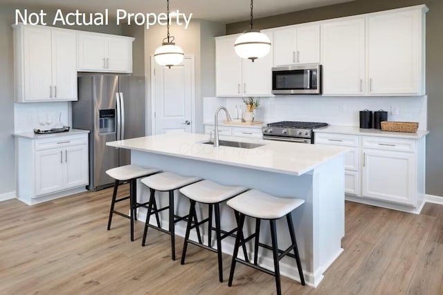 kitchen with white cabinetry, sink, tasteful backsplash, decorative light fixtures, and appliances with stainless steel finishes