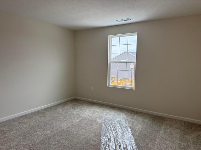 carpeted empty room featuring a textured ceiling