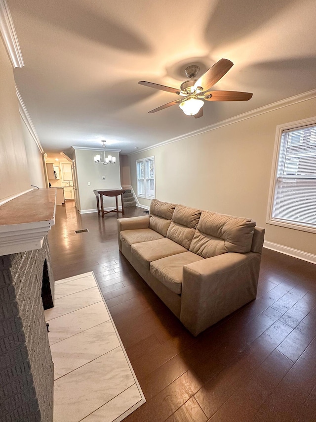 living room featuring a brick fireplace, a wealth of natural light, ceiling fan with notable chandelier, and hardwood / wood-style flooring