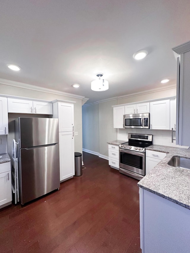 kitchen featuring light stone countertops, appliances with stainless steel finishes, dark hardwood / wood-style floors, and white cabinetry