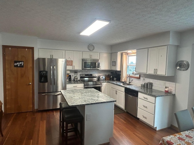 kitchen with a center island, sink, stainless steel appliances, dark hardwood / wood-style floors, and decorative backsplash