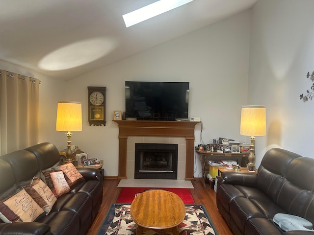 living room with a tile fireplace, lofted ceiling with skylight, and dark hardwood / wood-style flooring