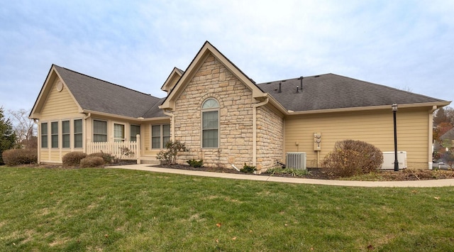 rear view of house with a lawn, a sunroom, and central AC unit