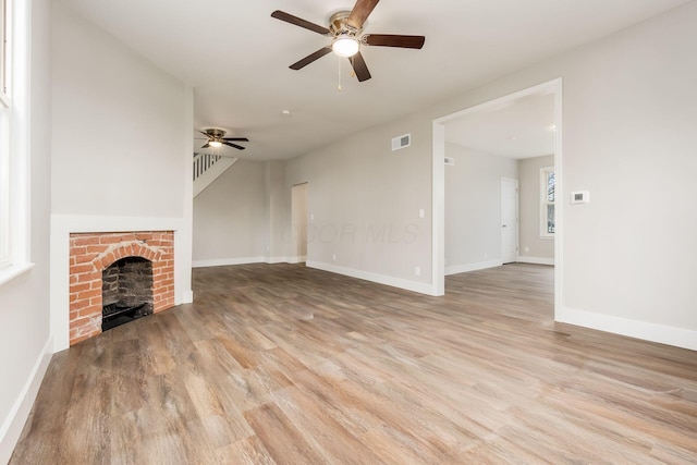 unfurnished living room with ceiling fan, light hardwood / wood-style floors, and a brick fireplace