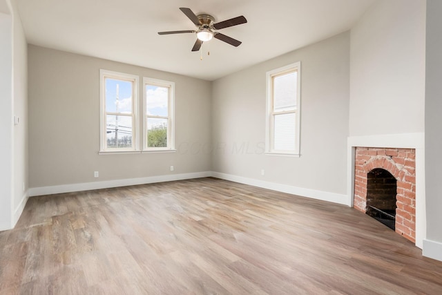 unfurnished living room with light hardwood / wood-style floors, a brick fireplace, and ceiling fan