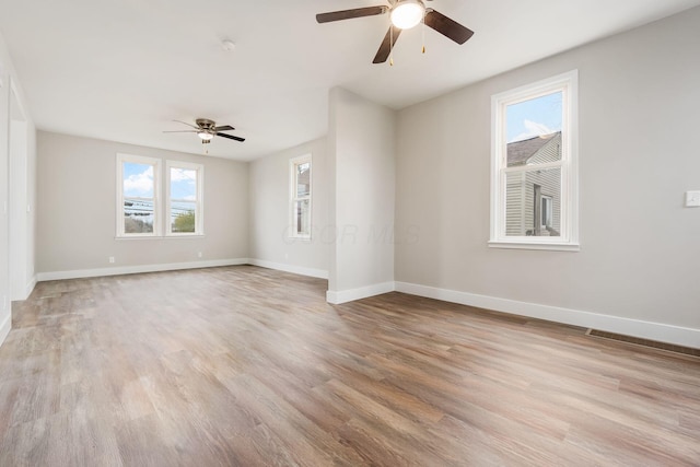 spare room with ceiling fan, plenty of natural light, and light wood-type flooring