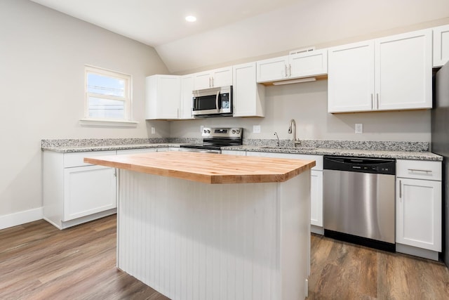 kitchen featuring wooden counters, stainless steel appliances, vaulted ceiling, sink, and white cabinets