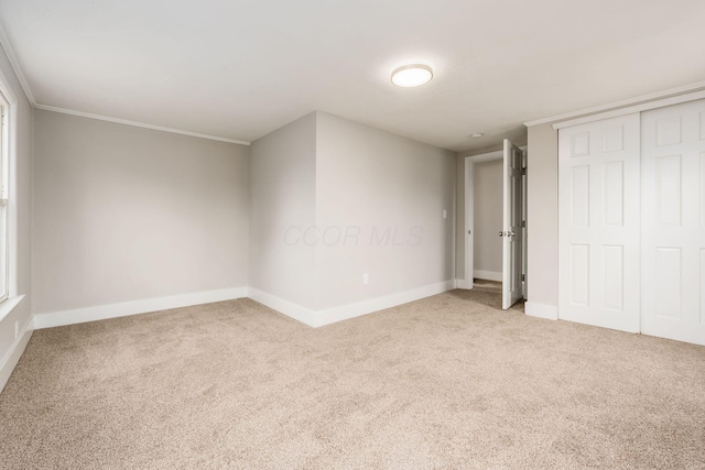 unfurnished bedroom featuring crown molding, a closet, and light colored carpet