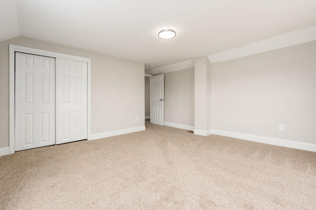 unfurnished bedroom featuring carpet, a closet, and lofted ceiling