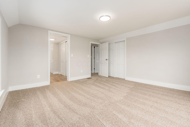 unfurnished bedroom with a closet, light colored carpet, and lofted ceiling