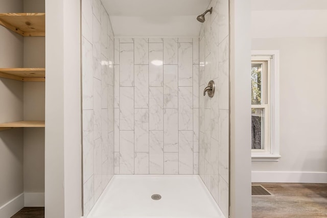 bathroom with tiled shower and hardwood / wood-style flooring