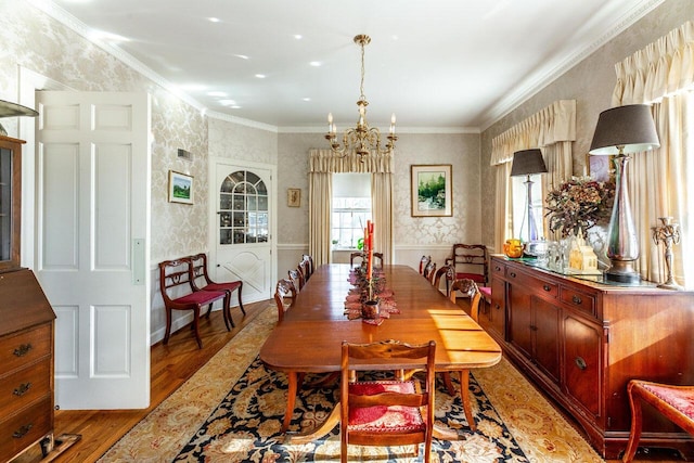 dining room with ornamental molding, a notable chandelier, and light wood-type flooring