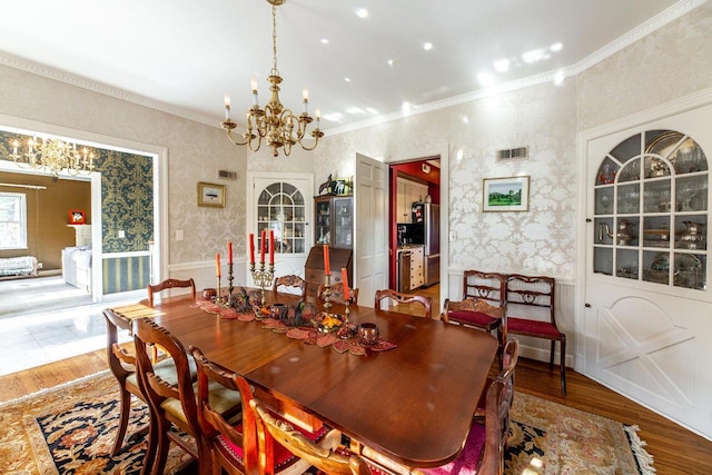 dining area featuring wood-type flooring, crown molding, and an inviting chandelier