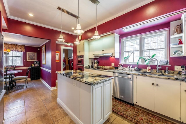 kitchen featuring washer and clothes dryer, pendant lighting, sink, appliances with stainless steel finishes, and white cabinetry