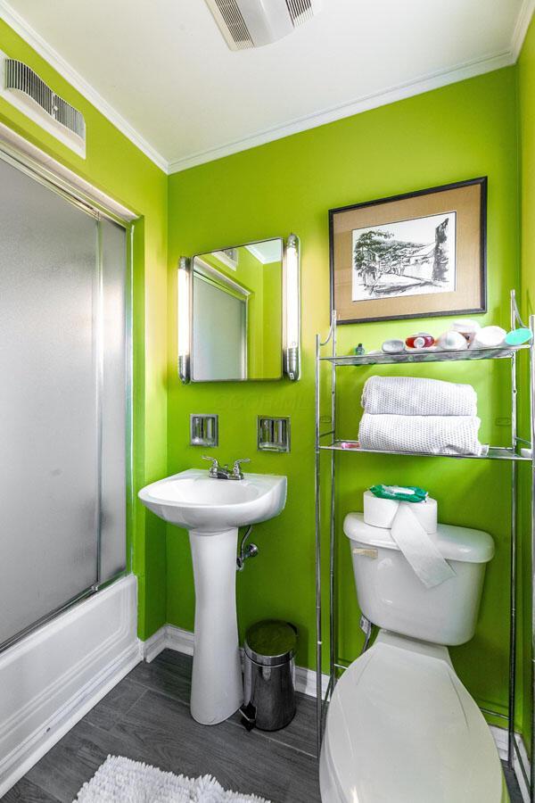 bathroom featuring hardwood / wood-style flooring, crown molding, and bath / shower combo with glass door