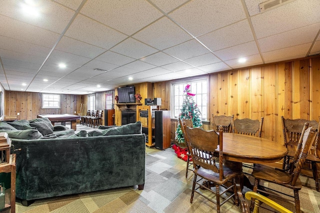 living room with a paneled ceiling and wooden walls