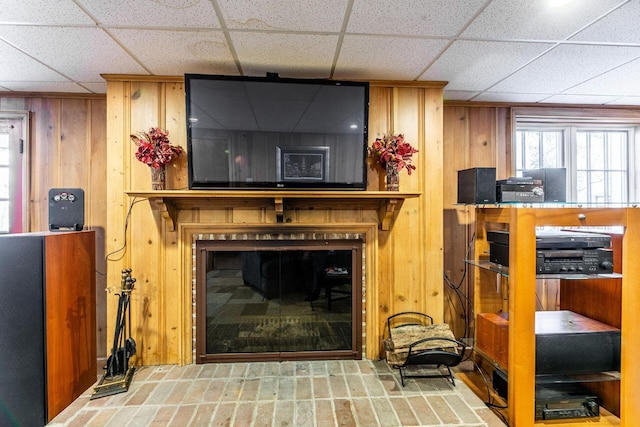 living room featuring a paneled ceiling and wooden walls