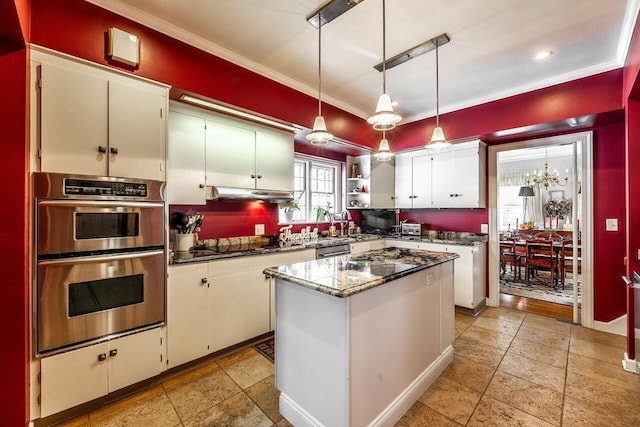 kitchen featuring appliances with stainless steel finishes, decorative light fixtures, dark stone countertops, a center island, and white cabinetry