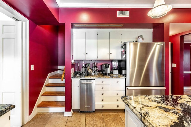 kitchen with white cabinetry, dark stone countertops, stainless steel fridge, and crown molding