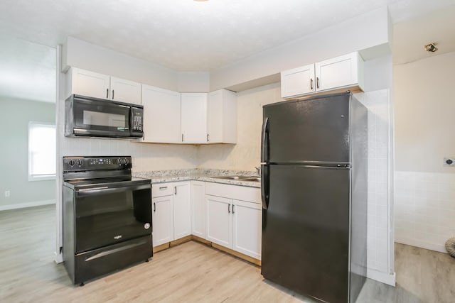 kitchen with white cabinetry, light hardwood / wood-style flooring, and black appliances