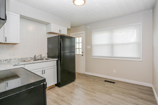 kitchen with black fridge, light hardwood / wood-style flooring, white cabinetry, and sink