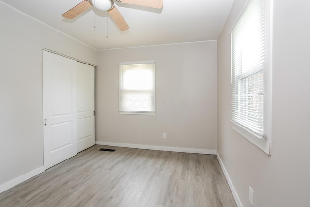 unfurnished bedroom with ceiling fan, a closet, and light wood-type flooring