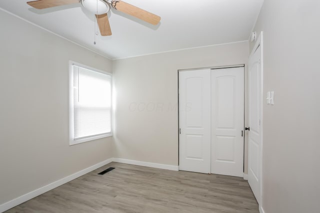 unfurnished bedroom featuring ceiling fan, light wood-type flooring, and a closet