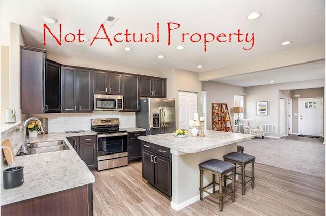 kitchen featuring a kitchen island, sink, light wood-type flooring, and stainless steel appliances