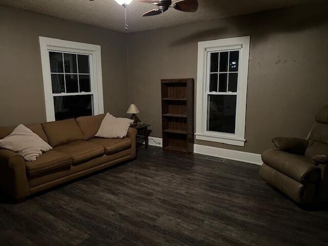 living room featuring ceiling fan, dark wood-type flooring, and a textured ceiling