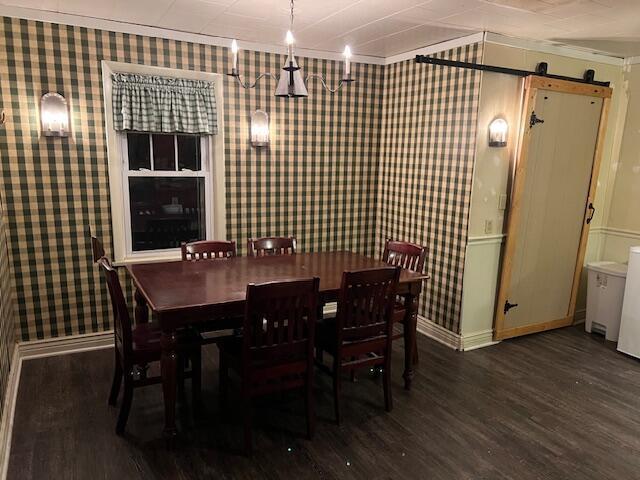 dining room with a barn door and dark hardwood / wood-style floors