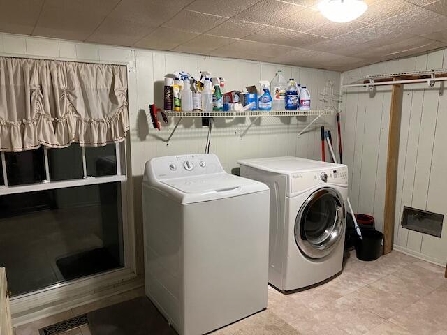 clothes washing area with wooden walls and washer and dryer