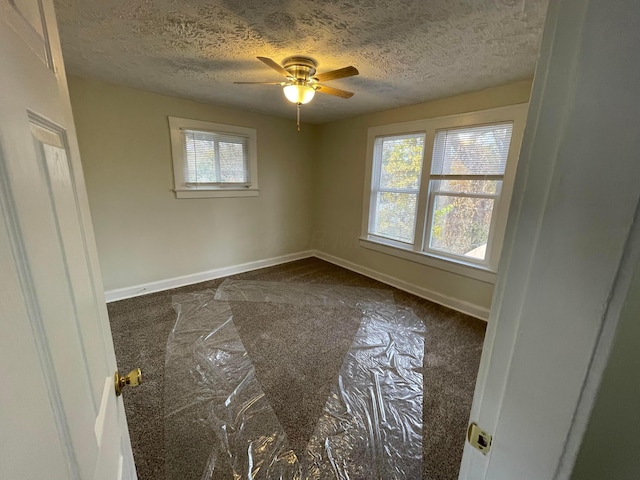 carpeted spare room with ceiling fan and a textured ceiling