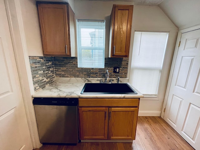 kitchen featuring dishwasher, sink, vaulted ceiling, decorative backsplash, and light hardwood / wood-style floors