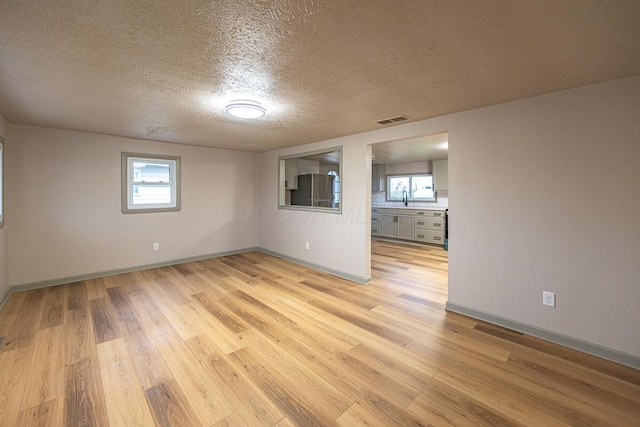 empty room featuring sink, light hardwood / wood-style floors, and a textured ceiling