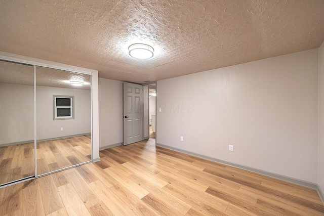 unfurnished bedroom with light wood-type flooring, a textured ceiling, and a closet