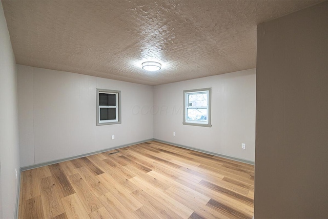 unfurnished room with light hardwood / wood-style floors and a textured ceiling