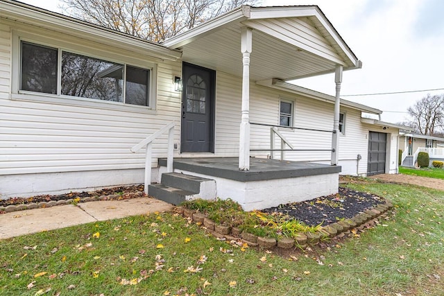 view of exterior entry featuring a yard and a porch