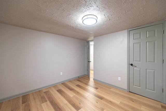 spare room featuring a textured ceiling and light hardwood / wood-style flooring