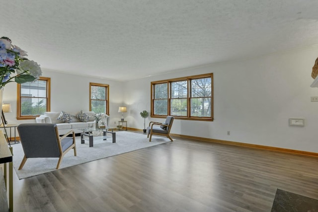 unfurnished living room featuring a textured ceiling, hardwood / wood-style flooring, crown molding, and a healthy amount of sunlight