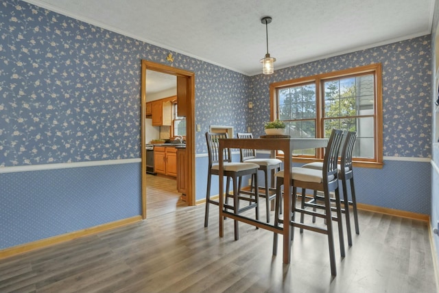 dining space featuring sink, ornamental molding, a textured ceiling, and hardwood / wood-style flooring