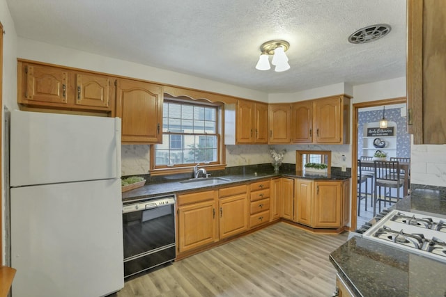 kitchen with light wood-type flooring, a textured ceiling, sink, white refrigerator, and black dishwasher