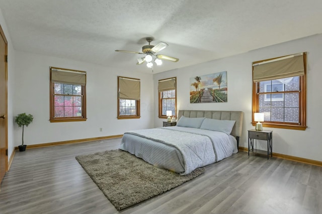 bedroom featuring multiple windows, ceiling fan, and a textured ceiling