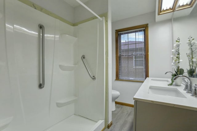 bathroom with vanity, toilet, wood-type flooring, and a shower